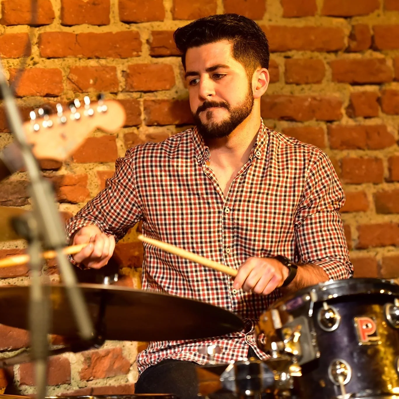 Oscar playing an acoustic kit with sticks and cymbals visible