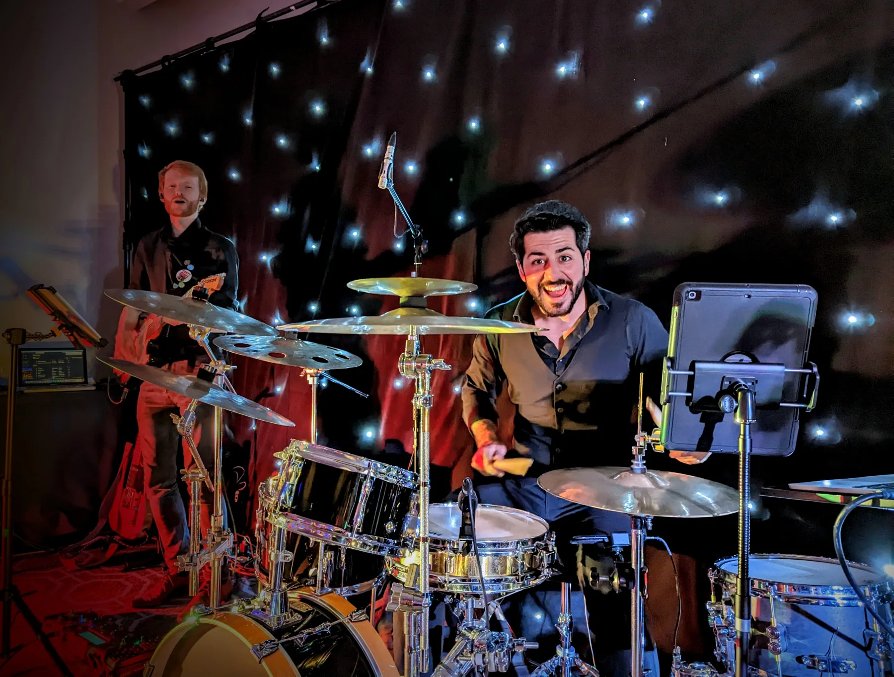 Oscar Lopez smiling behind his drum kit during a live performance