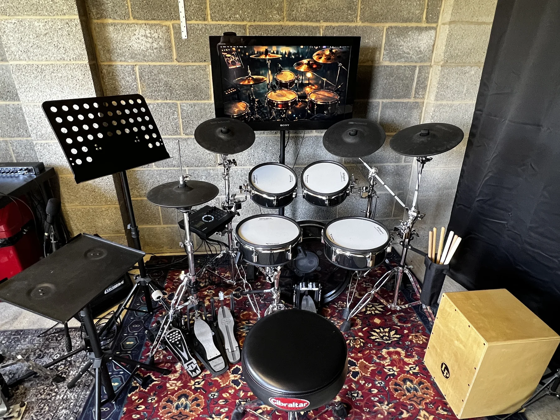 Electronic drum kit, stool, music stand and cajón in Oscar’s drum studio